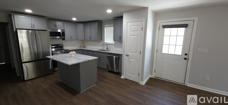 A kitchen with a refrigerator, sink, and cabinets.