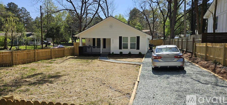 A small white house with a car parked in front.