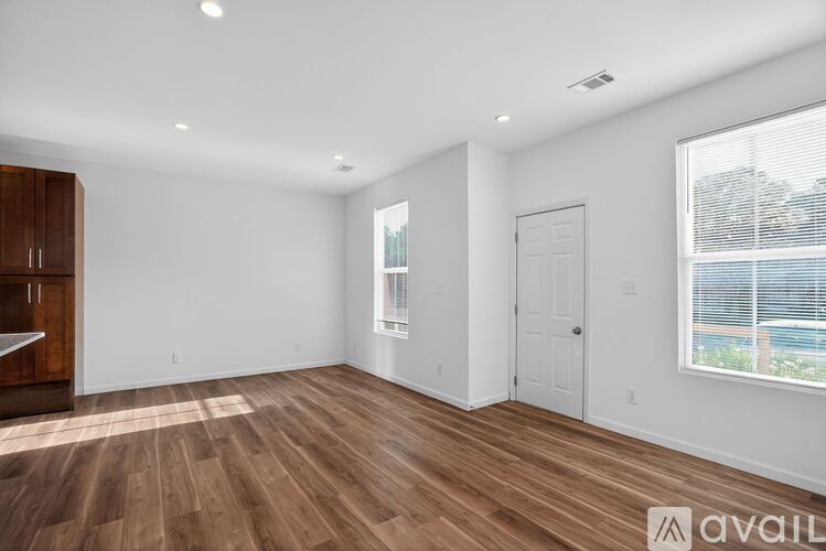 A spacious room with wooden flooring and white walls.