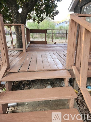 A wooden deck with a bench and a tree.