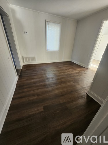 A room with wooden flooring and a window.
