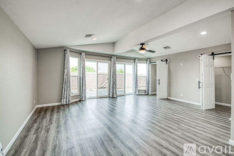 A spacious room with a ceiling fan and sliding glass doors.