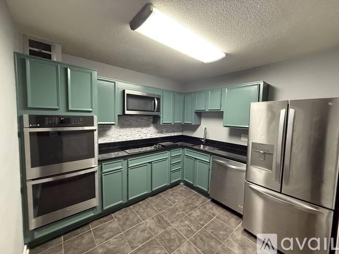 A kitchen with green cabinets and stainless steel appliances.