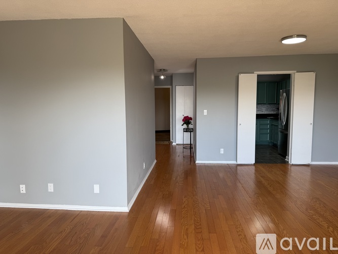 A spacious room with wooden flooring and a doorway leading to another room.