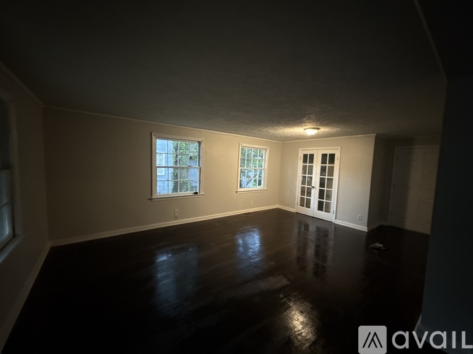 A room with two windows and a door is available for rent.