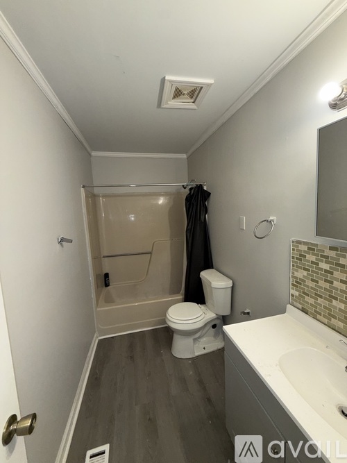 A small, clean bathroom with a toilet, sink, and shower.