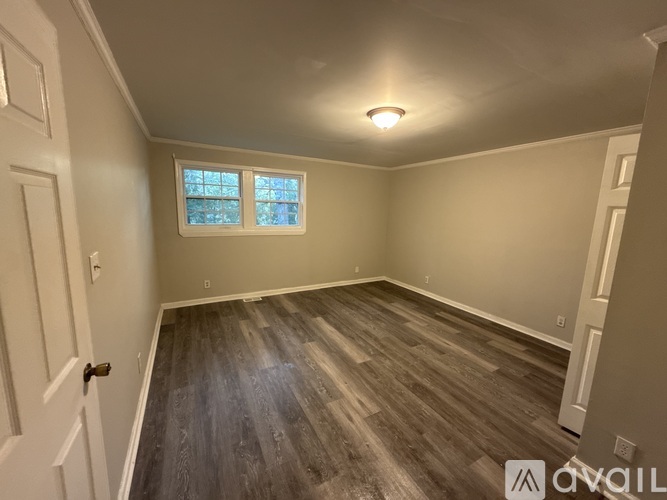 A room with wooden flooring and a window.