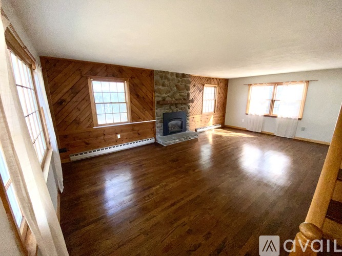 A spacious living room with wood flooring and a stone fireplace.