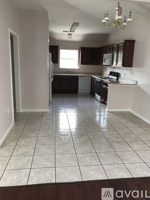 A kitchen with white tiled floors and dark brown cabinets.