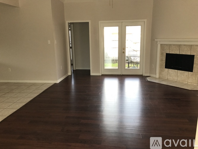 A spacious room with a fireplace and a door leading to a balcony.