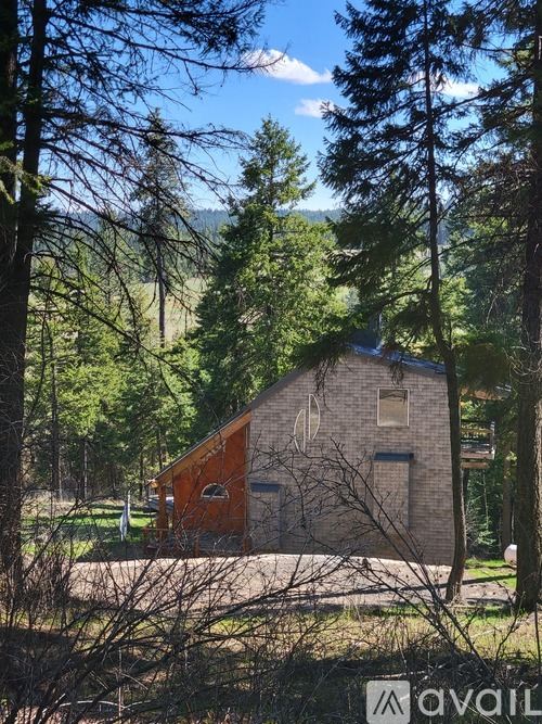 A house with a brown roof is surrounded by trees.