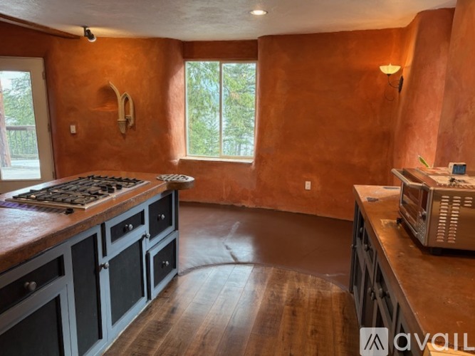 A kitchen with a wooden floor and a stove top oven.