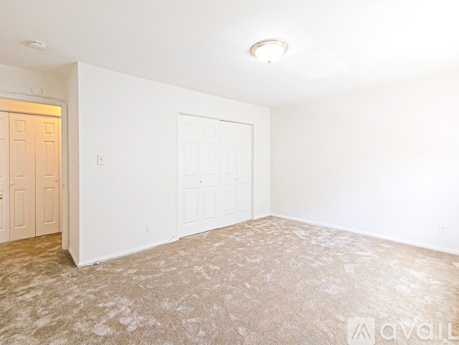 A room with a carpeted floor and two doors.