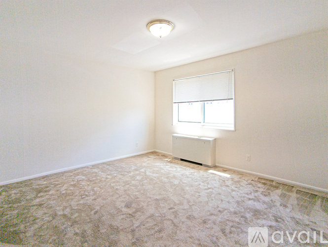 A room with a carpeted floor and a window with blinds.