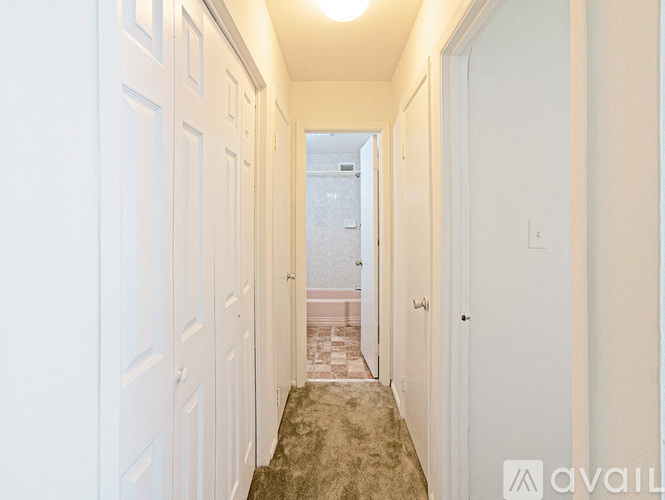 A hallway with a carpeted floor and white walls.