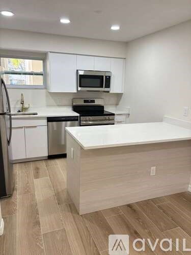 A kitchen with white cabinets and a wooden floor.