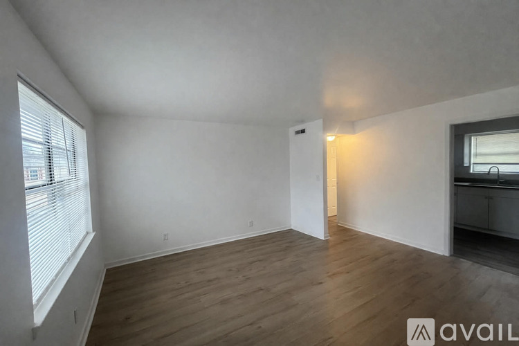 A spacious room with wooden flooring and white walls.