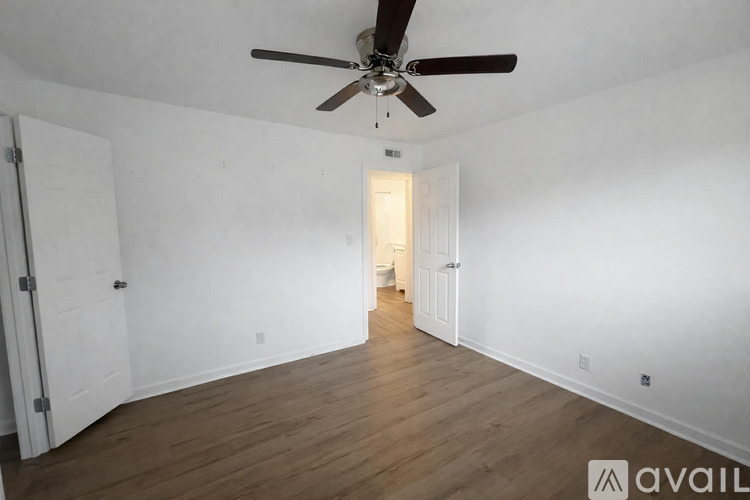 A room with a ceiling fan and wooden flooring.