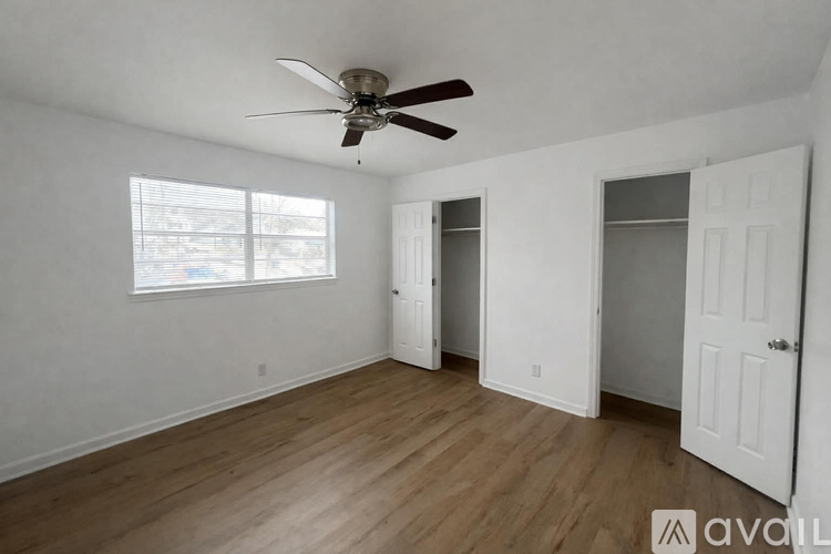 A room with a ceiling fan and wooden flooring.