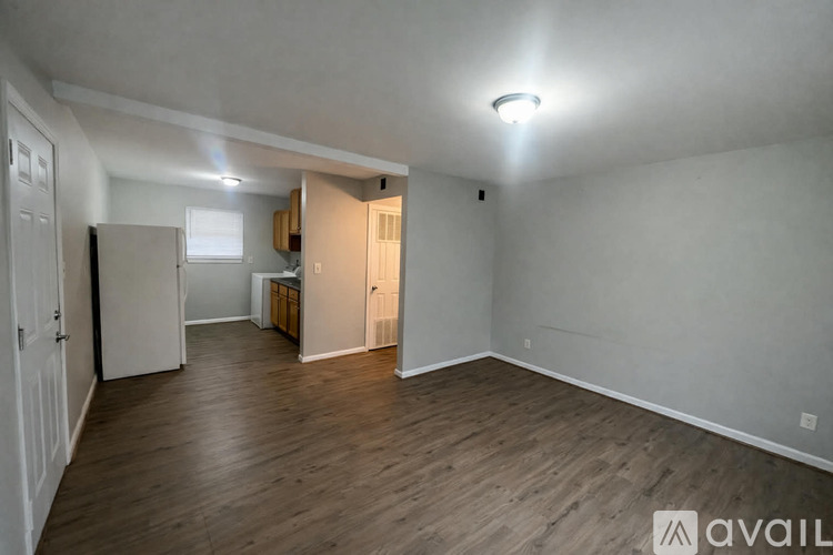 A spacious room with wooden flooring and white walls.
