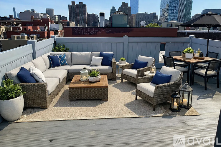 A patio with a white couch, blue pillows, and a wooden table.
