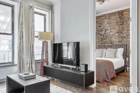 A bedroom with a brick wall and a bed with a red and white blanket.