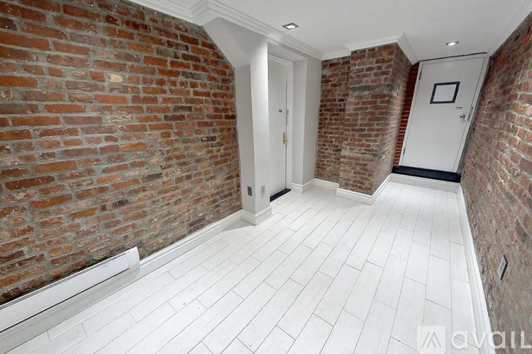 A hallway with a brick wall and white tile flooring.