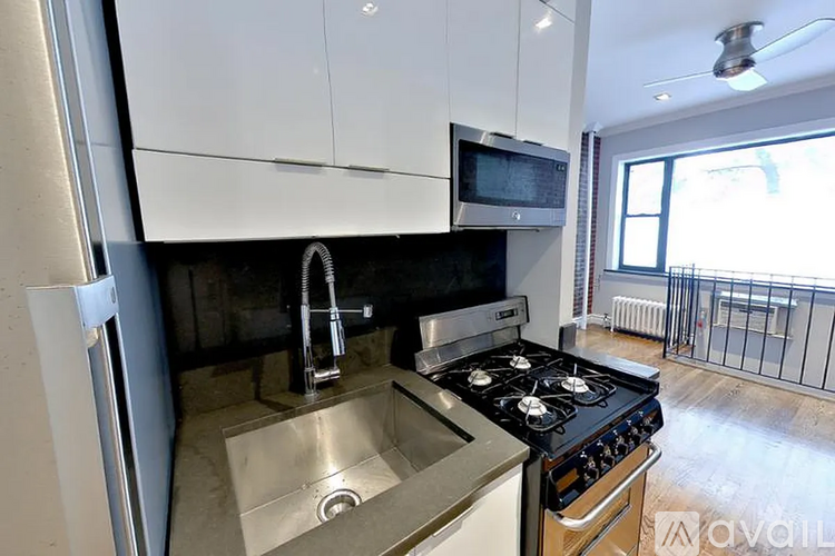 A modern kitchen with a stove, sink, and microwave.