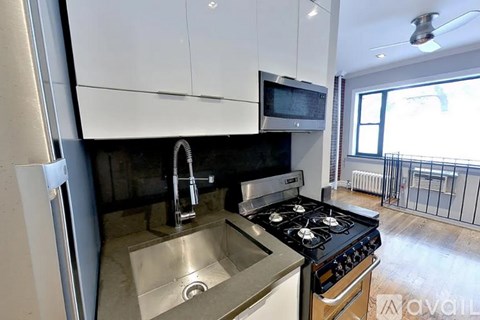 A modern kitchen with a stove, sink, and microwave.
