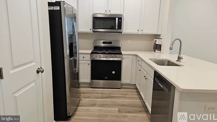 A kitchen with a black refrigerator and white cabinets.