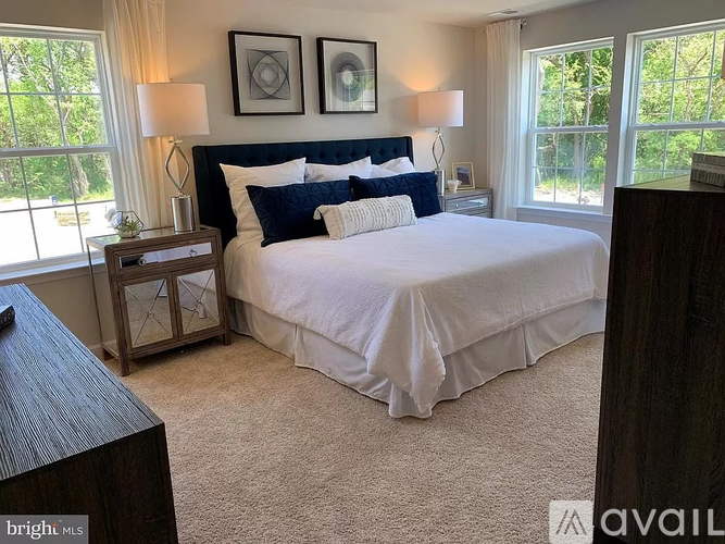 A bedroom with a large bed and a nightstand with a lamp.