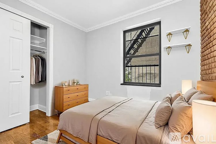A bedroom with a bed, dresser, and a window with a fire escape.
