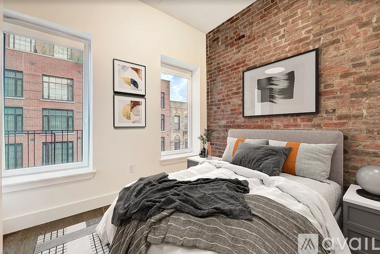 A bedroom with a brick wall and a bed with a striped comforter.