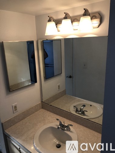 A bathroom with a sink, mirror, and lighting fixture.