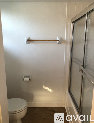 A white toilet in a small bathroom with a towel bar and a window.