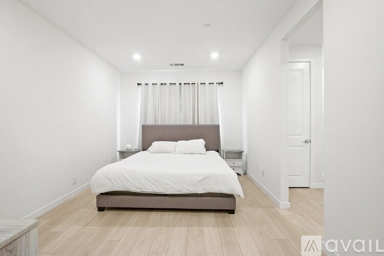 A bedroom with a bed, nightstand, and window with curtains.