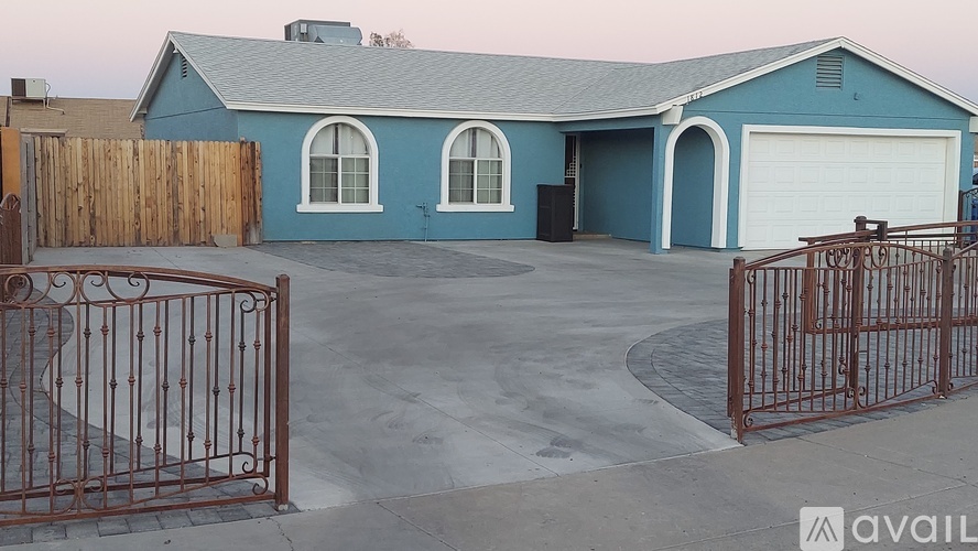 A blue house with a garage and a gate in front.