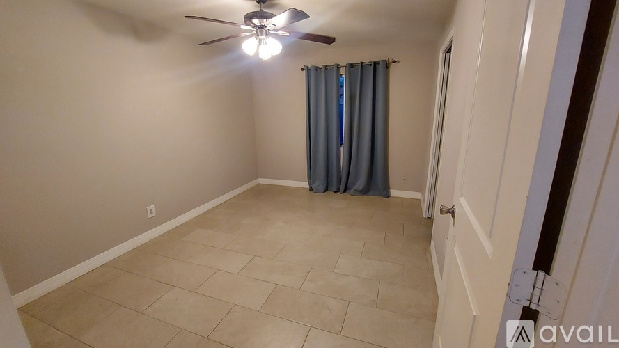 A room with a ceiling fan and a window with blue curtains.