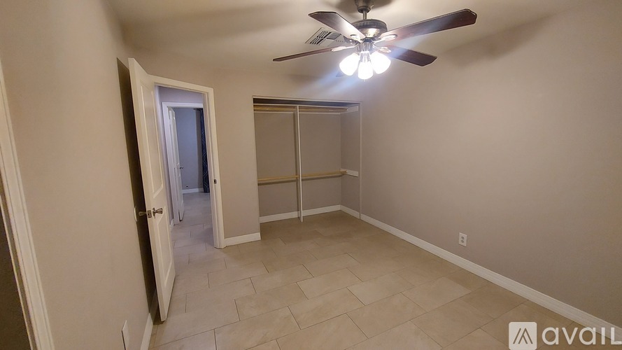 A room with a ceiling fan and a door leading to another room.