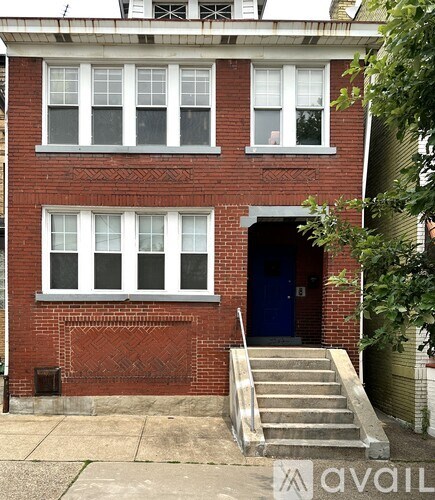 A red brick building with a blue door and a set of stairs leading up to it.