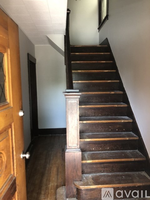 A wooden staircase with a white wall and a door on the left.