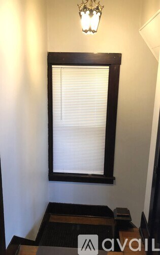 A window with blinds and a chandelier in a room.