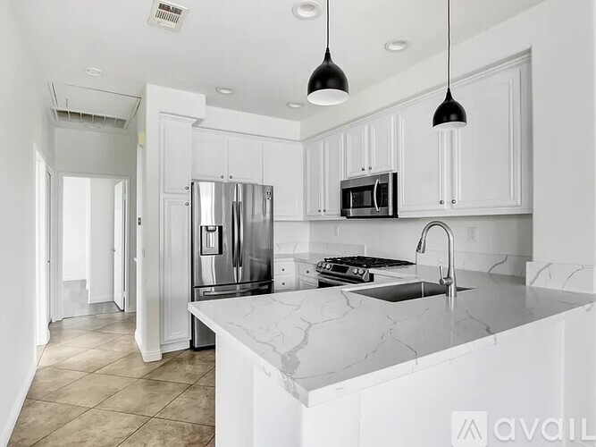 A modern kitchen with white cabinets and a marble countertop.