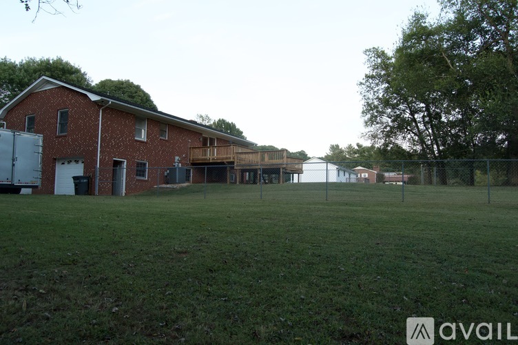 A red brick building with a white door and windows is surrounded by a green field.