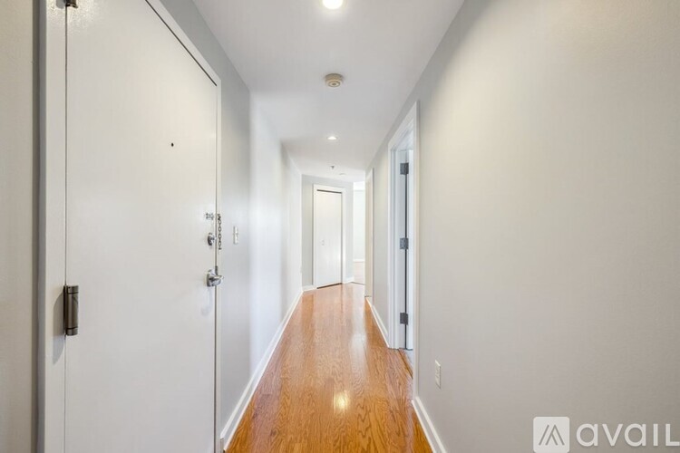 A long hallway with a wooden floor and white walls.