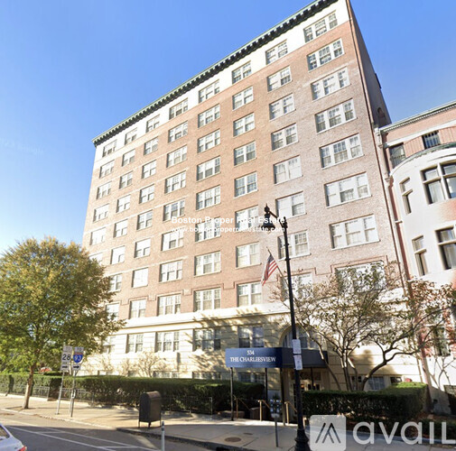 A tall building with many windows is located on a street corner.