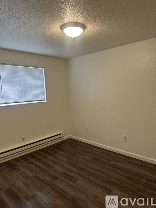 A room with a window and wooden flooring.