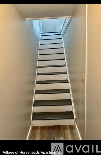A staircase in a white hallway leading to a door.