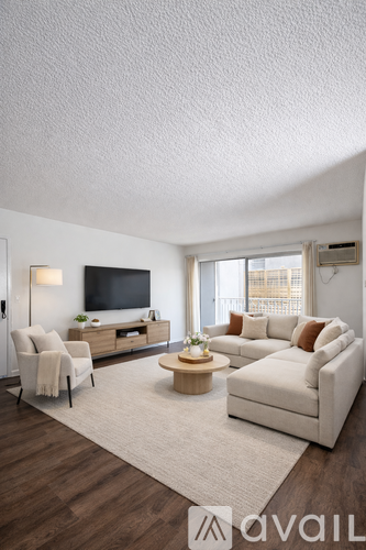 A living room with a white couch, a wooden coffee table, and a flat-screen TV mounted on the wall.