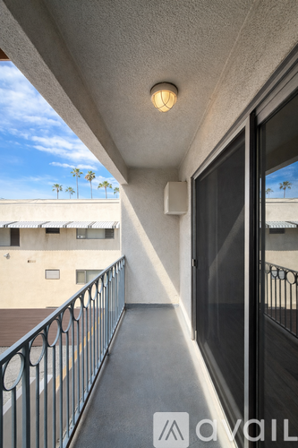 A balcony with a metal railing and a window overlooking a building.